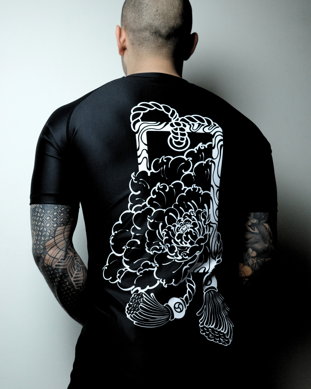 grappler holding 10 pack of finger tape with white finger tape wrapped around his fingers. Grappler is wearing kakuto culture's rashie.